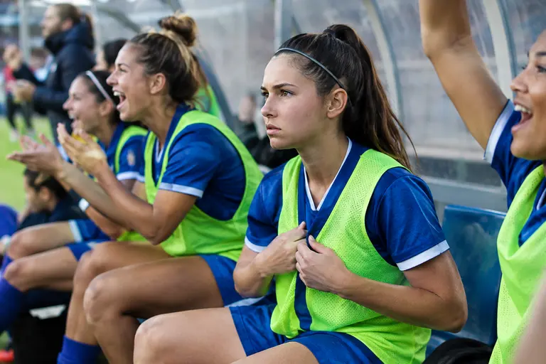 USWNT substitutes warming up along the sideline during an evening match